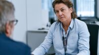 Mitarbeiterin in Beratungsgespräch mit diskretem Alarmknopf am Arbeitsplatz
